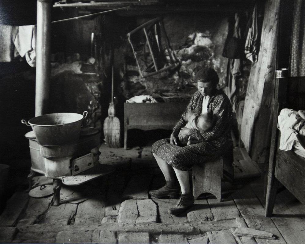 Woman nursing baby near wood stove, Savoie